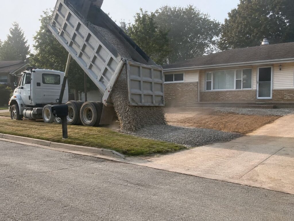 Tandem dump truck unloading gravel at suburban home