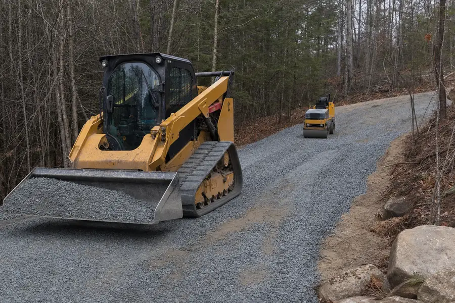 Contractor spreading and compacting crusher run base for a gravel driveway