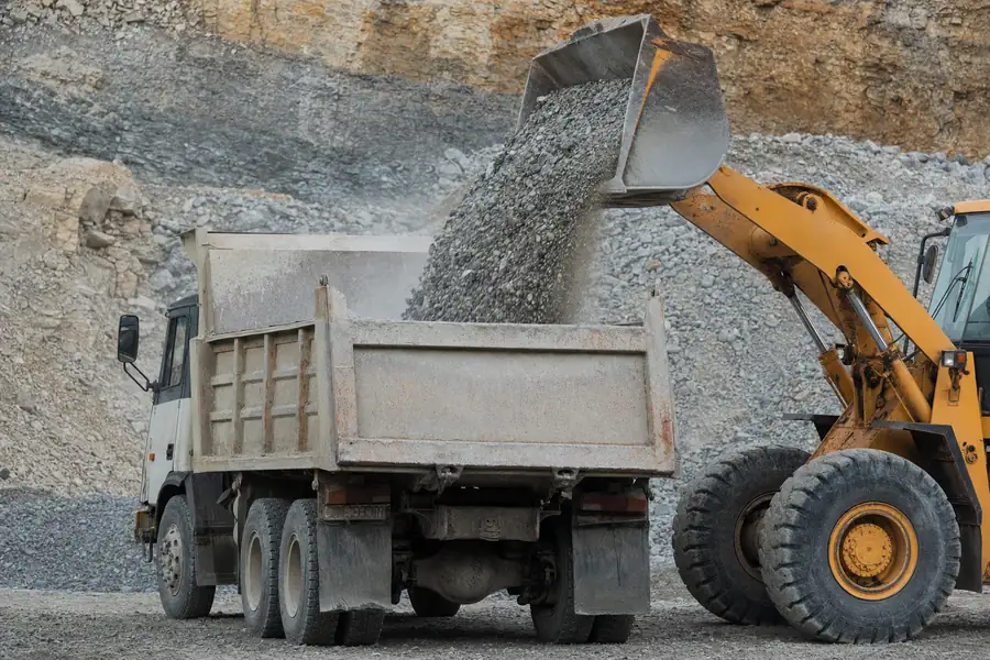 Loader dumping crushed stone into a delivery truck at a rock quarry