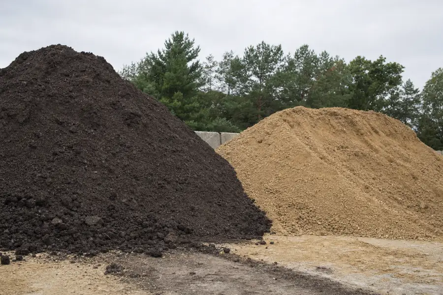Side-by-side piles of dark topsoil and tan fill dirt at a supply yard