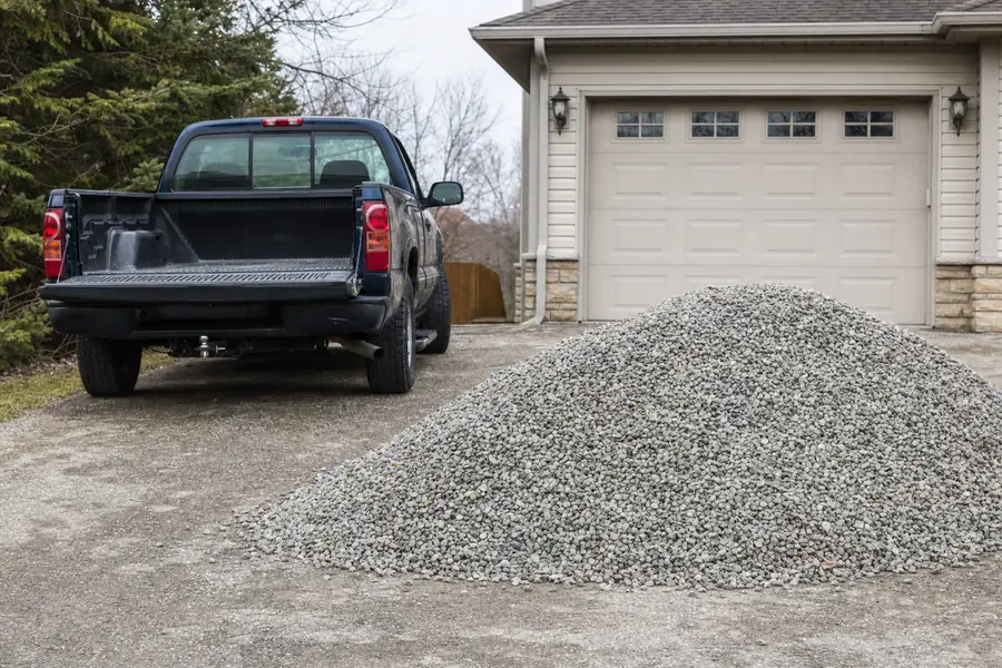 Pickup truck and gravel pile in a suburban driveway ready for spreading