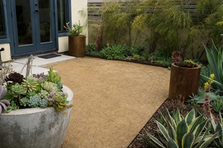 Small courtyard patio in decomposed granite framed by steel edging and potted succulents