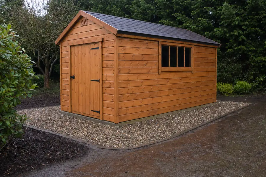 Photo of a finished wooden garden shed sitting proud on its gravel foundation after rain: water visibly drained away from the base, stone apron extending a foot beyond the walls on all sides, wet timber and clean stone glistening, overcast soft light proving the drainage story